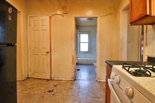 kitchen with black refrigerator and white range with gas cooktop