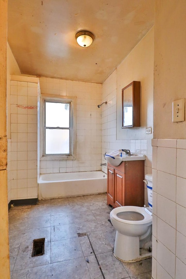 full bathroom featuring tiled shower / bath, vanity, tile walls, and toilet