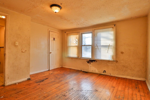 spare room featuring hardwood / wood-style floors and a textured ceiling