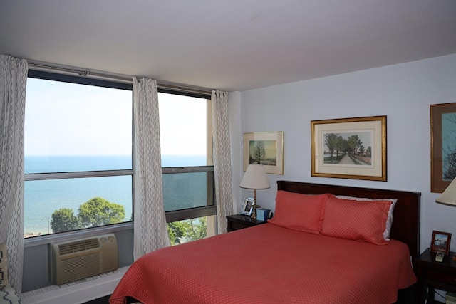 bedroom featuring a water view, an AC wall unit, and multiple windows