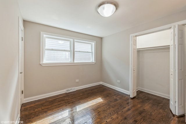 unfurnished bedroom featuring a closet and dark wood-type flooring