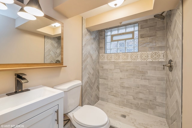 bathroom with toilet, oversized vanity, and a tile shower