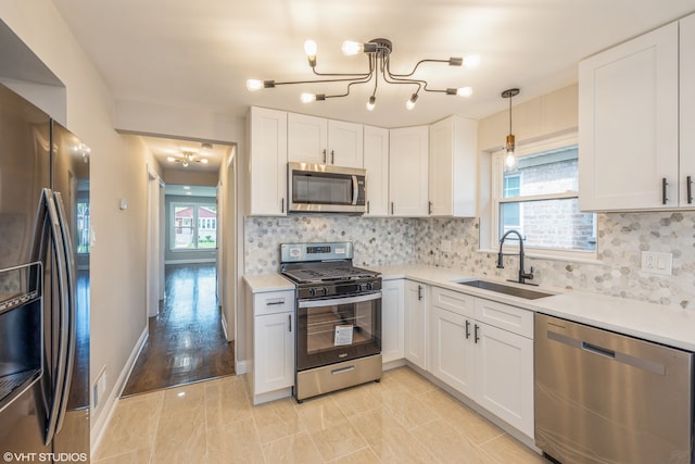 kitchen with backsplash, stainless steel appliances, sink, pendant lighting, and light tile floors