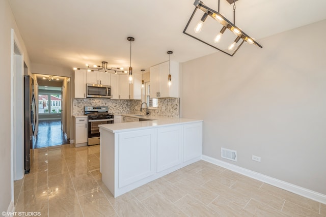 kitchen with appliances with stainless steel finishes, kitchen peninsula, light tile flooring, and white cabinets