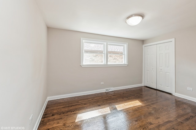 unfurnished bedroom featuring dark hardwood / wood-style flooring and a closet