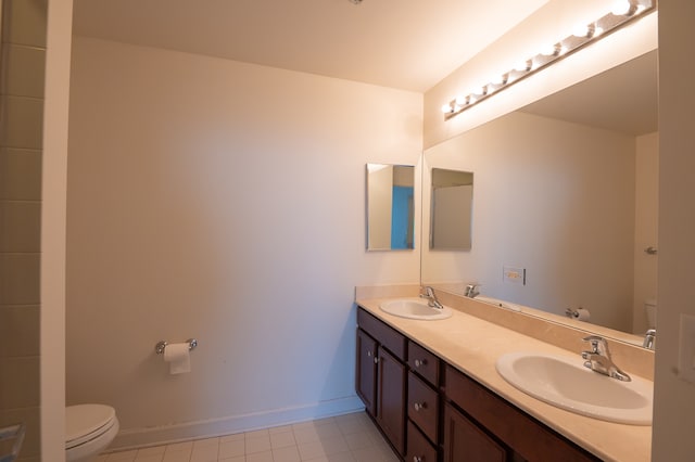 bathroom with toilet, double vanity, and tile patterned flooring