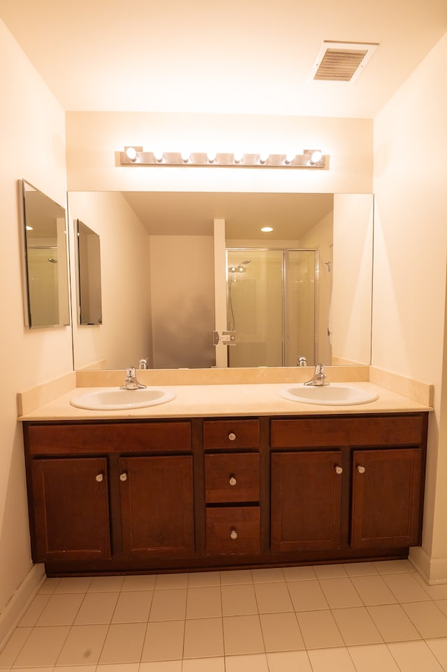 bathroom featuring tile patterned flooring, an enclosed shower, and dual bowl vanity