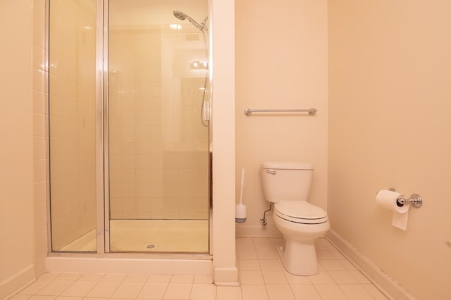 bathroom featuring tile patterned flooring, toilet, and walk in shower