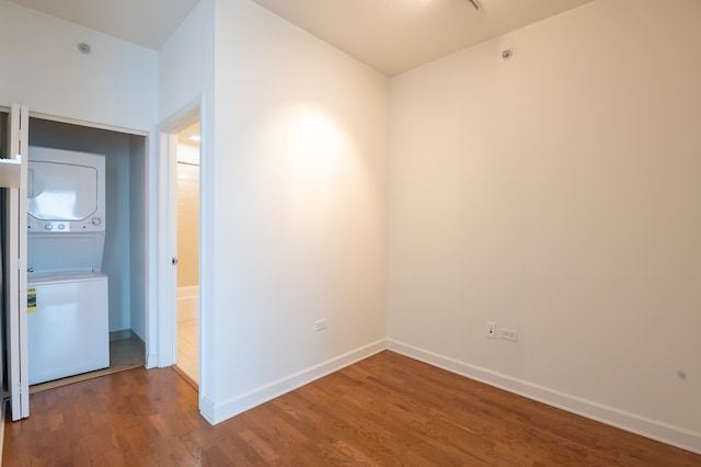 unfurnished room featuring stacked washer / dryer and wood-type flooring