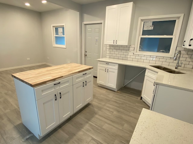 kitchen with white cabinetry, sink, backsplash, and hardwood / wood-style flooring