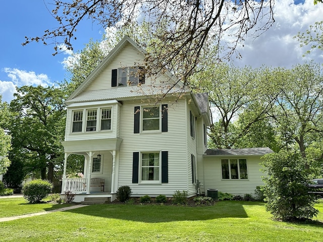 view of front of home with central AC, a front yard, and covered porch