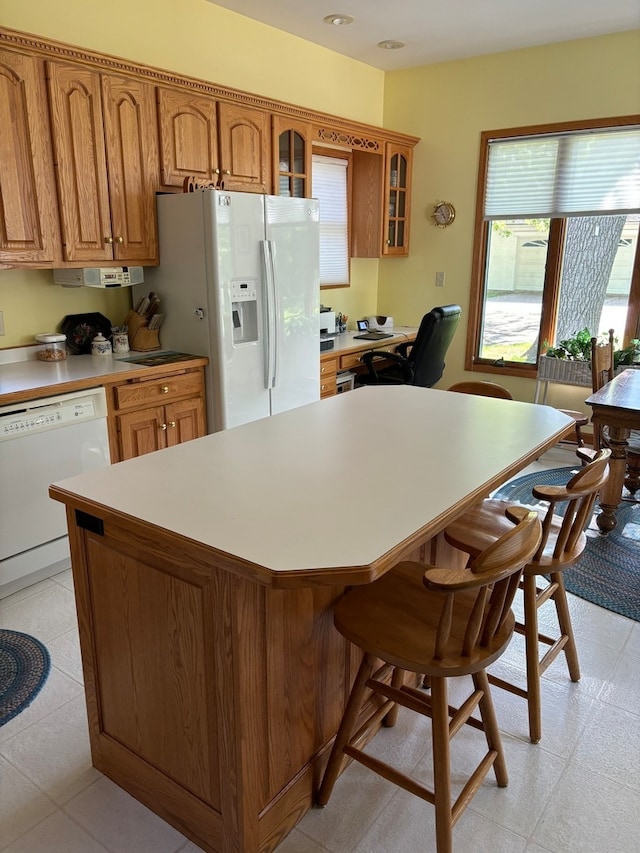 kitchen with white appliances, a kitchen breakfast bar, and light tile flooring