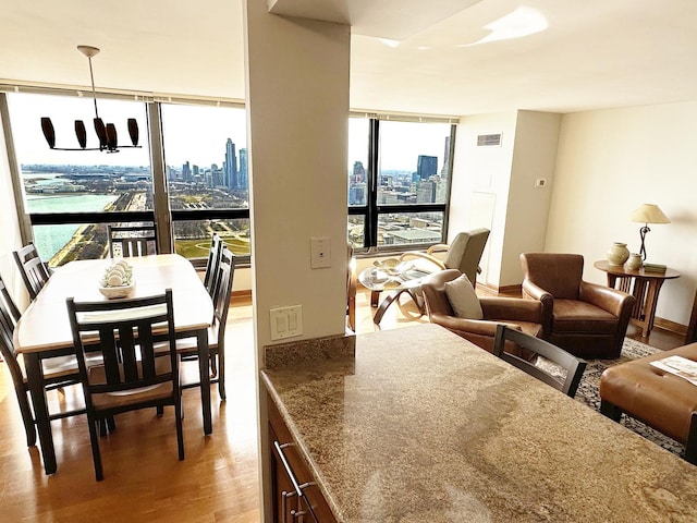 interior space with a chandelier, wood-type flooring, a water view, and floor to ceiling windows