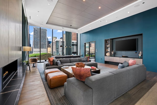 living room with a tray ceiling, dark hardwood / wood-style floors, a tile fireplace, and expansive windows