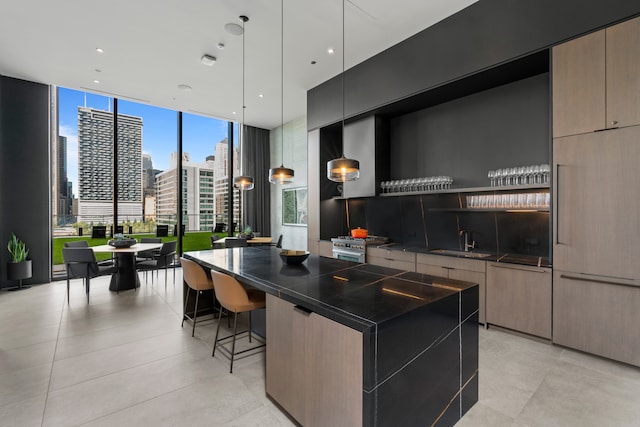 kitchen featuring a kitchen breakfast bar, hanging light fixtures, a kitchen island, a wall of windows, and sink