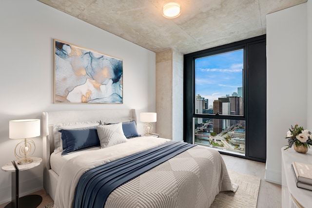 bedroom with floor to ceiling windows and light wood-type flooring