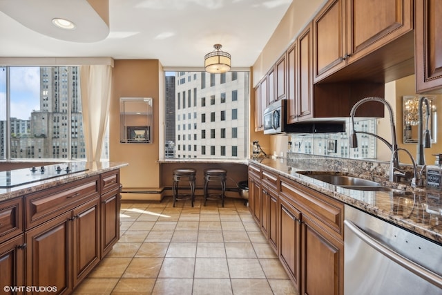 kitchen featuring dark stone countertops, appliances with stainless steel finishes, sink, and light tile floors