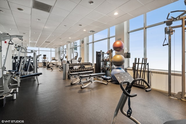 exercise room featuring a paneled ceiling and a wall of windows