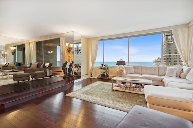 living room with dark wood-type flooring, a water view, and a chandelier