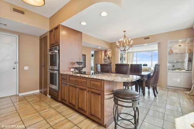 kitchen featuring light stone countertops, black electric stovetop, light tile flooring, a notable chandelier, and double oven