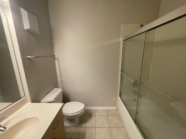 full bathroom with vanity, tile patterned flooring, shower / bath combination with glass door, and toilet