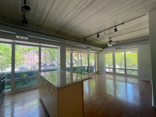 interior space with light wood-type flooring, a wealth of natural light, white cabinetry, and light stone counters