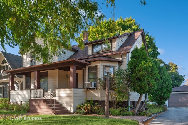 view of front of property featuring a garage, cooling unit, and covered porch