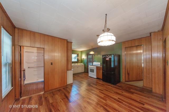 kitchen featuring dark wood-type flooring, wooden walls, white range oven, and black refrigerator