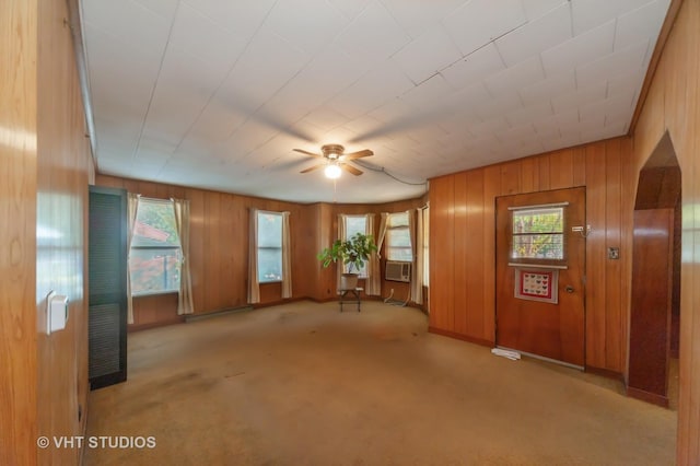 interior space featuring cooling unit, a ceiling fan, carpet flooring, and wooden walls