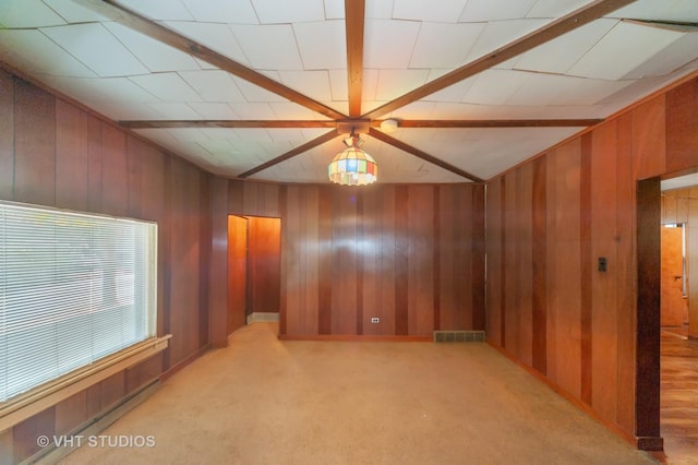spare room featuring light carpet, visible vents, and wooden walls
