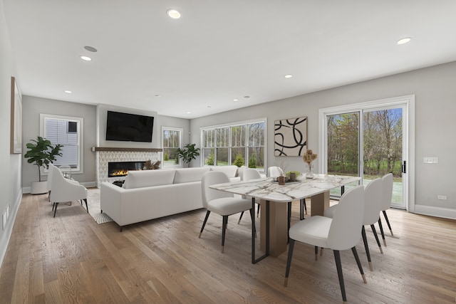 dining area with wood-type flooring, plenty of natural light, and a tile fireplace