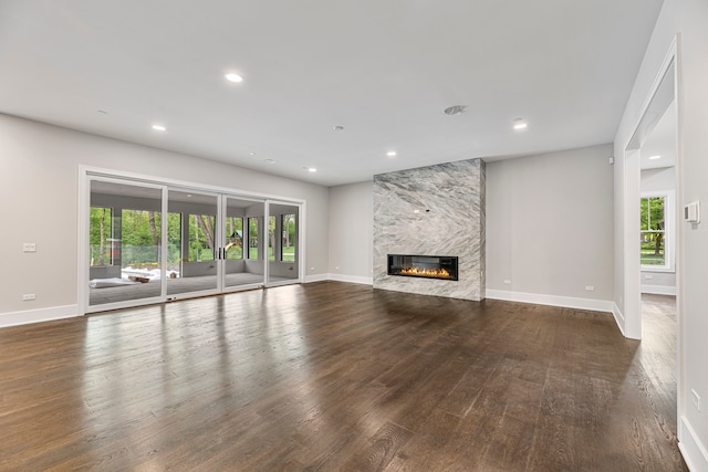 unfurnished living room with a wealth of natural light, dark wood-type flooring, and a fireplace