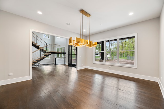 empty room with a notable chandelier and dark hardwood / wood-style floors