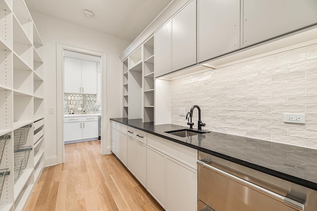 kitchen with open shelves, light wood-style flooring, decorative backsplash, and a sink