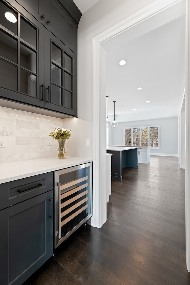 bar with wine cooler, tasteful backsplash, decorative light fixtures, and dark hardwood / wood-style flooring