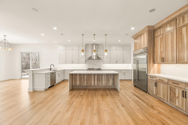 kitchen with a peninsula, wall chimney range hood, appliances with stainless steel finishes, and decorative backsplash