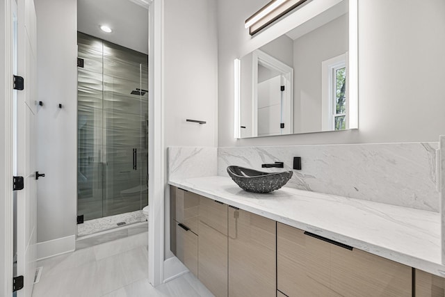 bathroom featuring tasteful backsplash, a shower stall, toilet, and vanity