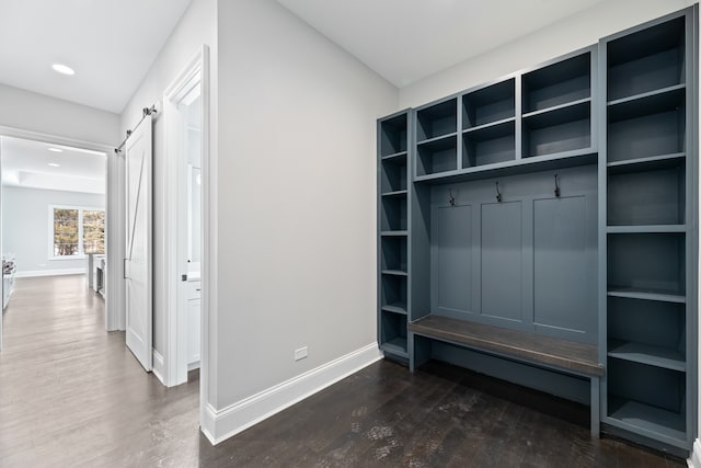 mudroom with a barn door and dark hardwood / wood-style flooring