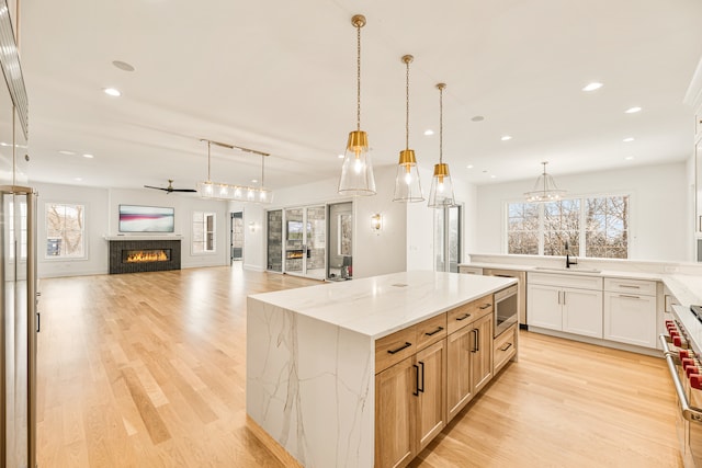 kitchen featuring light stone counters, hanging light fixtures, a spacious island, and sink