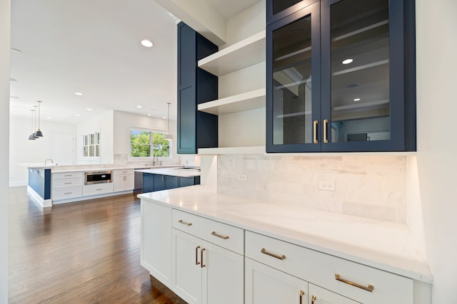 kitchen with pendant lighting, tasteful backsplash, white cabinetry, light stone countertops, and dark hardwood / wood-style flooring