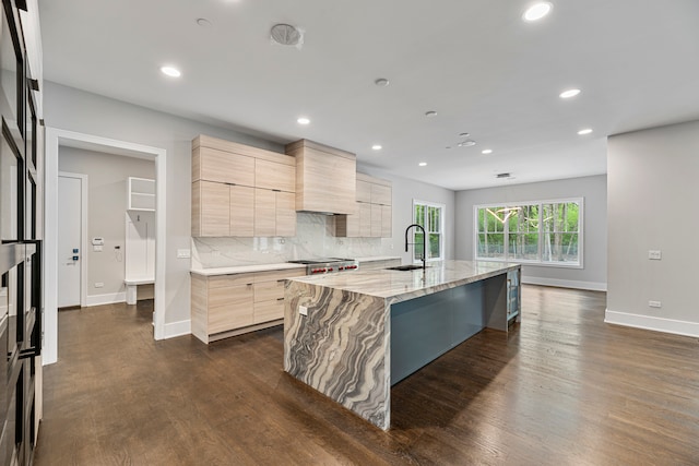 kitchen featuring backsplash, light brown cabinets, a center island with sink, dark hardwood / wood-style floors, and sink