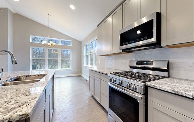 kitchen with light hardwood / wood-style floors, lofted ceiling, stainless steel appliances, backsplash, and sink