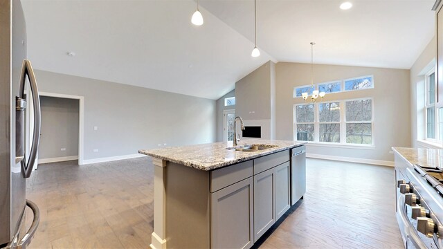 kitchen with gray cabinetry, stainless steel appliances, an island with sink, light hardwood / wood-style flooring, and sink