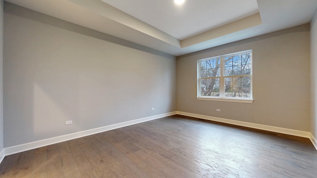 empty room featuring dark hardwood / wood-style floors and a raised ceiling