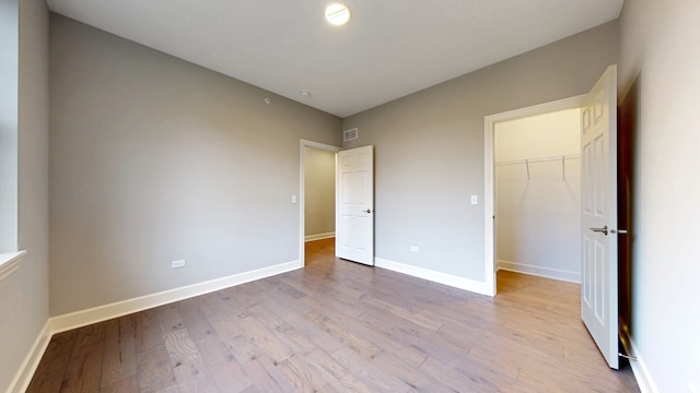 unfurnished bedroom featuring a spacious closet, a closet, and wood-type flooring