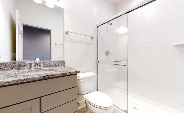 bathroom featuring vanity with extensive cabinet space, an enclosed shower, and toilet