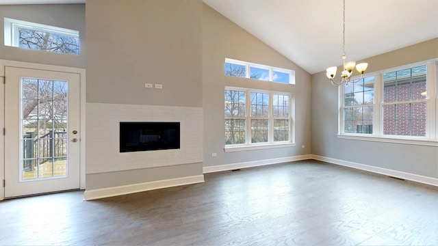 unfurnished living room with a brick fireplace, high vaulted ceiling, dark hardwood / wood-style flooring, and a chandelier