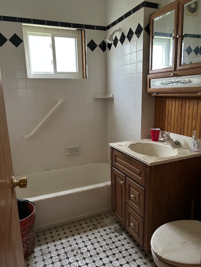 full bathroom with tiled shower / bath, tile flooring, toilet, and vanity