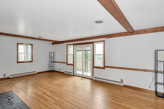 empty room featuring baseboard heating, plenty of natural light, and light hardwood / wood-style flooring