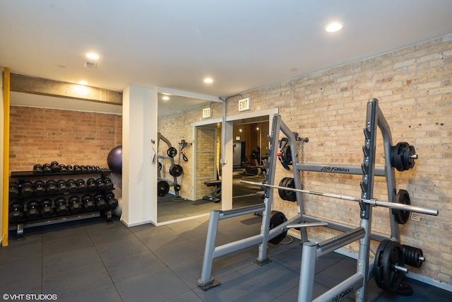 workout room with dark tile floors and brick wall